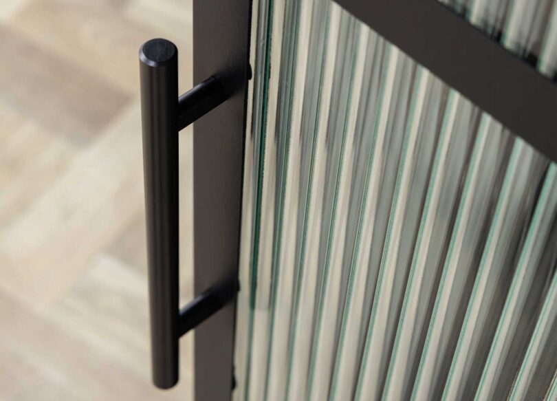 porte avec poignee en metal noir et facade verre strie