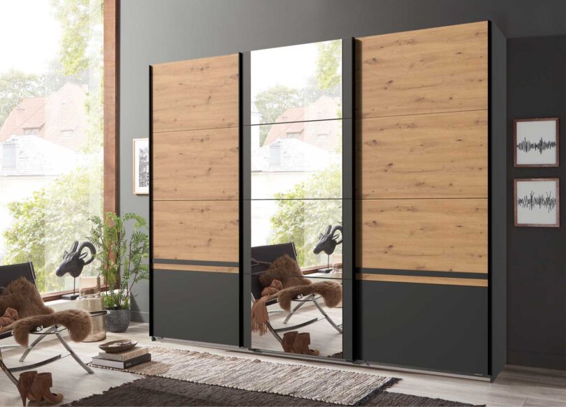 armoire 270 cm 3 portes coulissantes avec miroir couleur chene artisan et gris graphite avec un tapis et un fauteuil papillon
