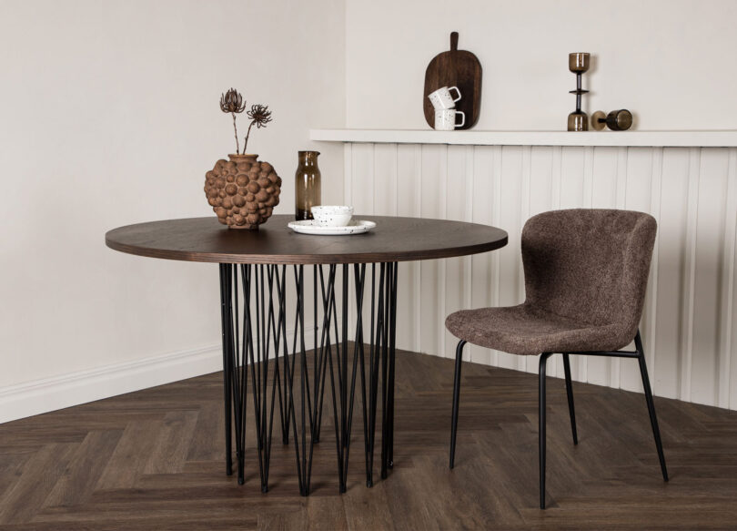 table de salle à manger aspect bois foncé et un pieds design en métal noir pour 4 personnes