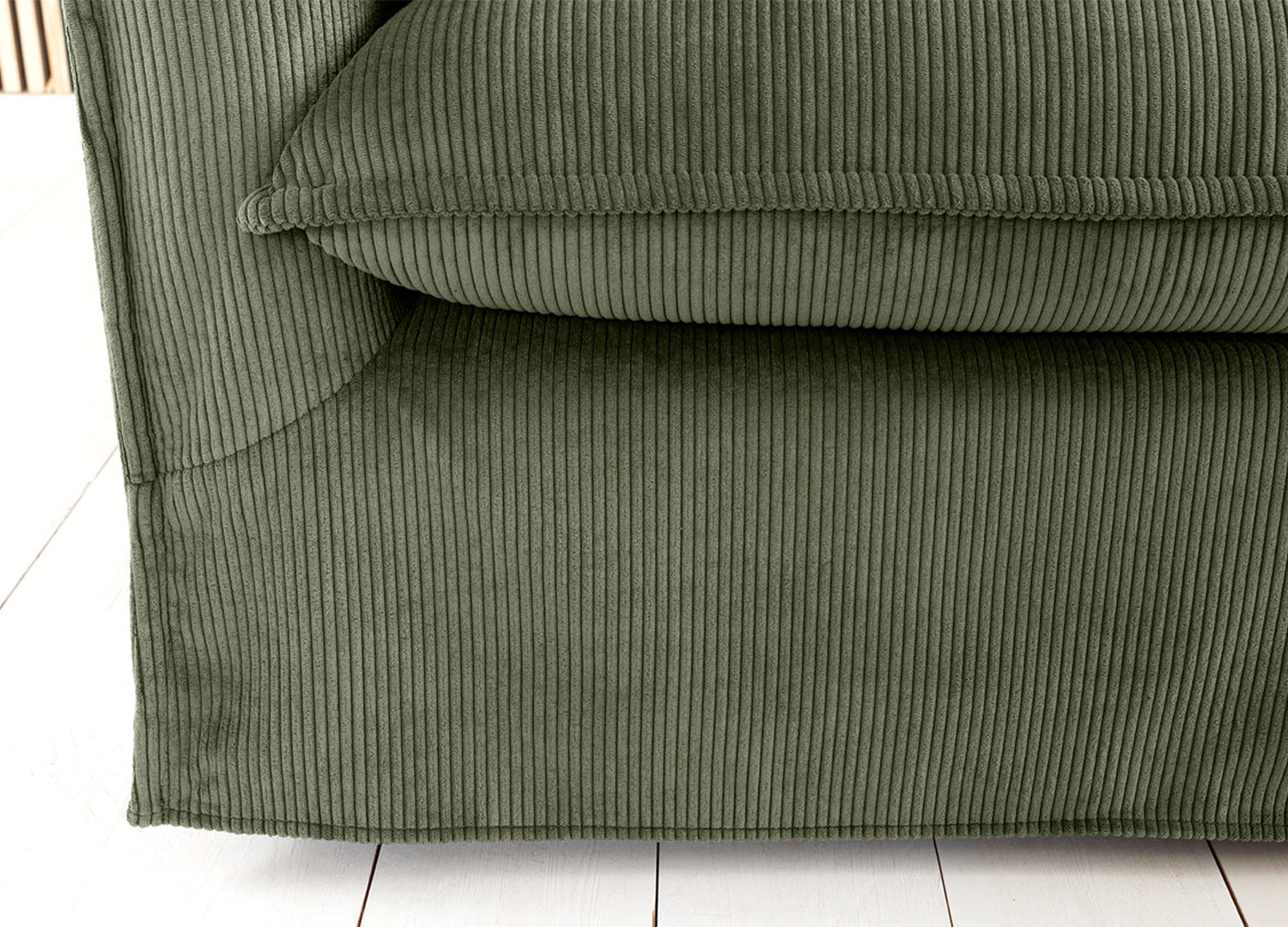 Détail de l’assise et de la base du canapé MILO en velours côtelé vert