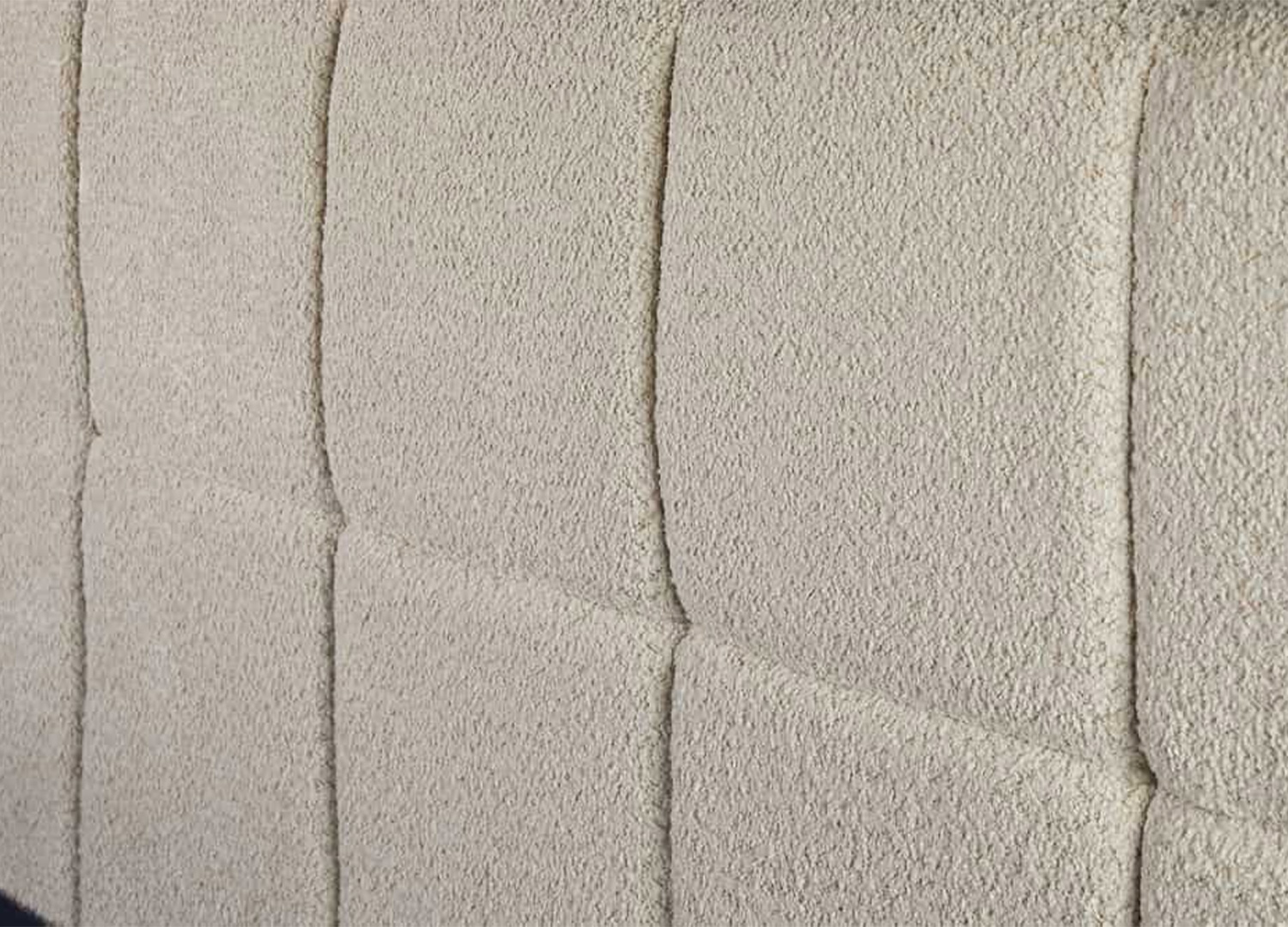 Détail de la finition rembourrée de la tête de lit MÉRÉA recouverte de tissu bouclé crème