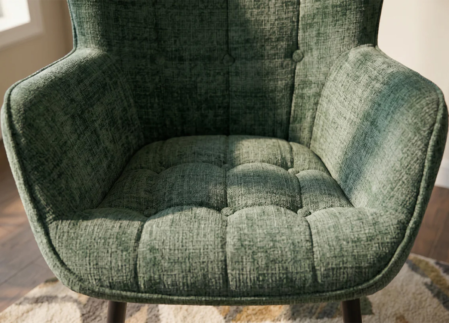 Gros plan sur l’assise capitonnée et les accoudoirs rembourrés du fauteuil SÉLÈNE vert
