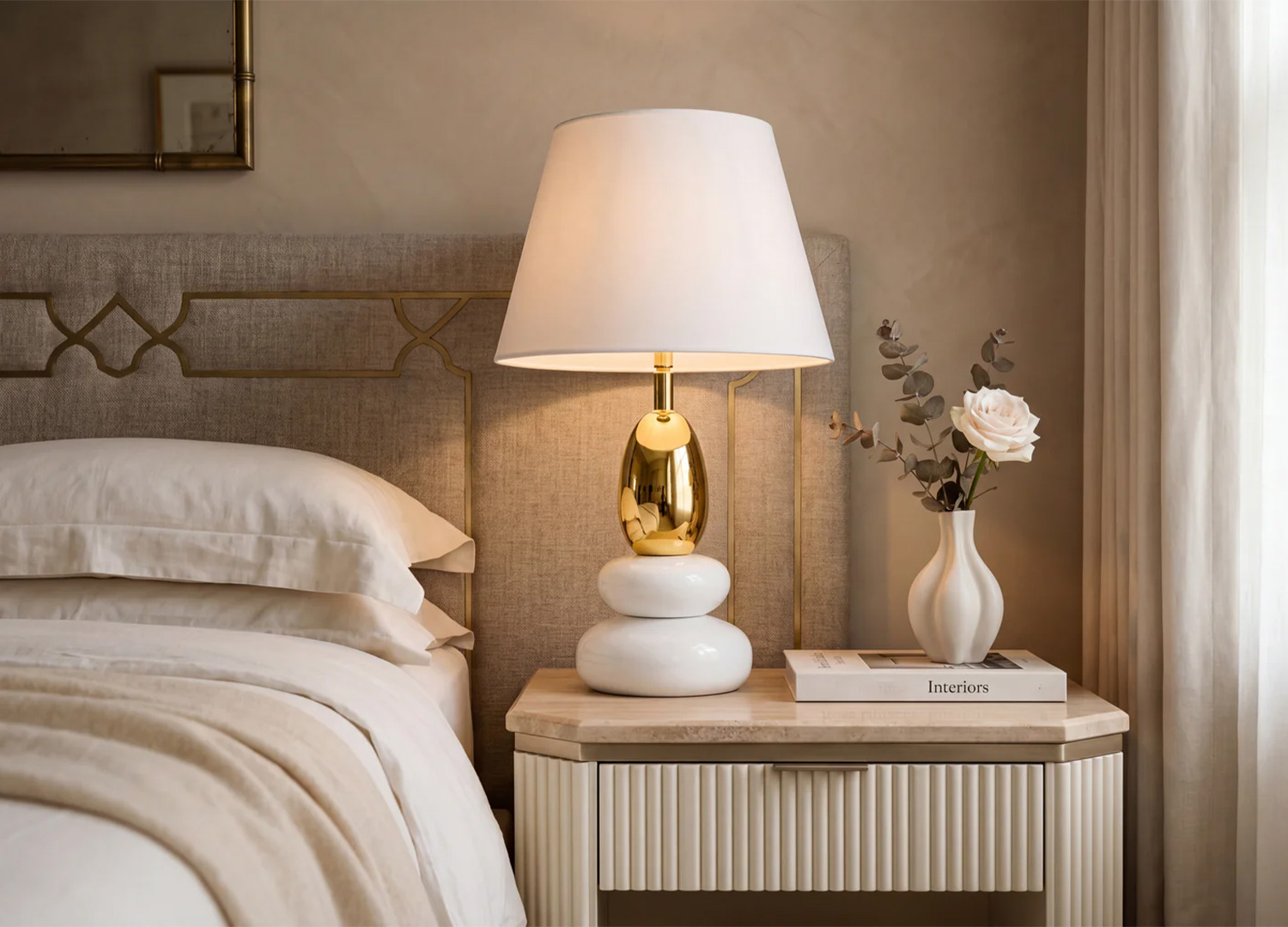 Lampe à poser AURÉA blanc et or sur table de chevet dans une chambre chaleureuse