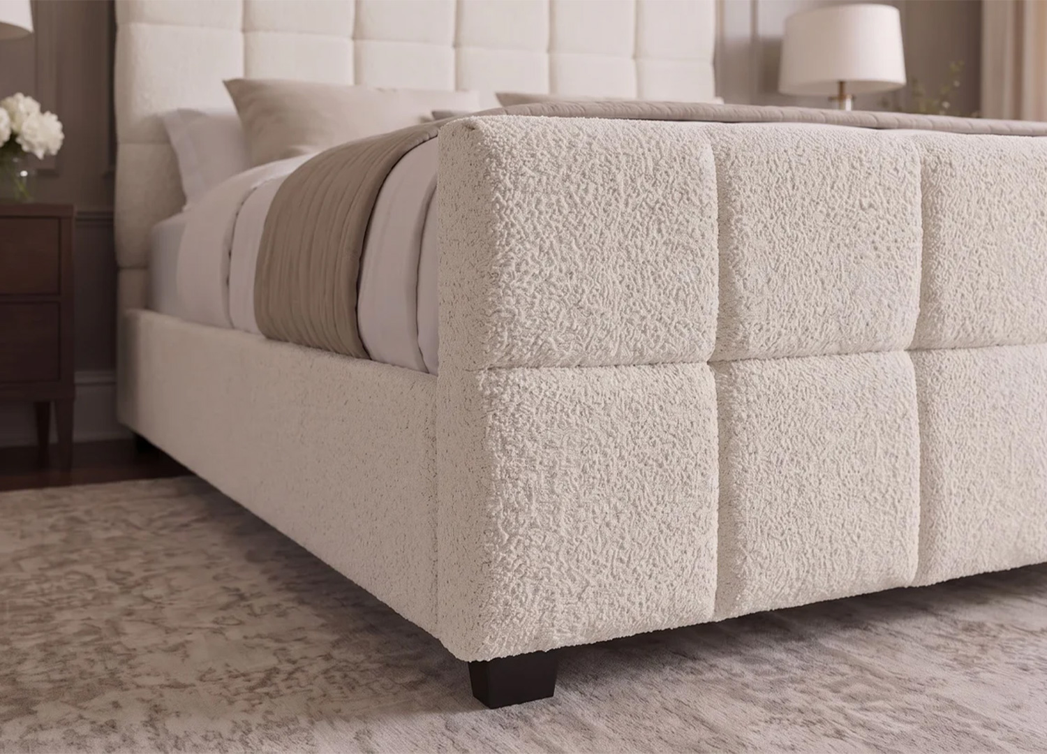 Détail du pied de lit capitonné MÉRÉA en tissu bouclé crème avec pieds noirs