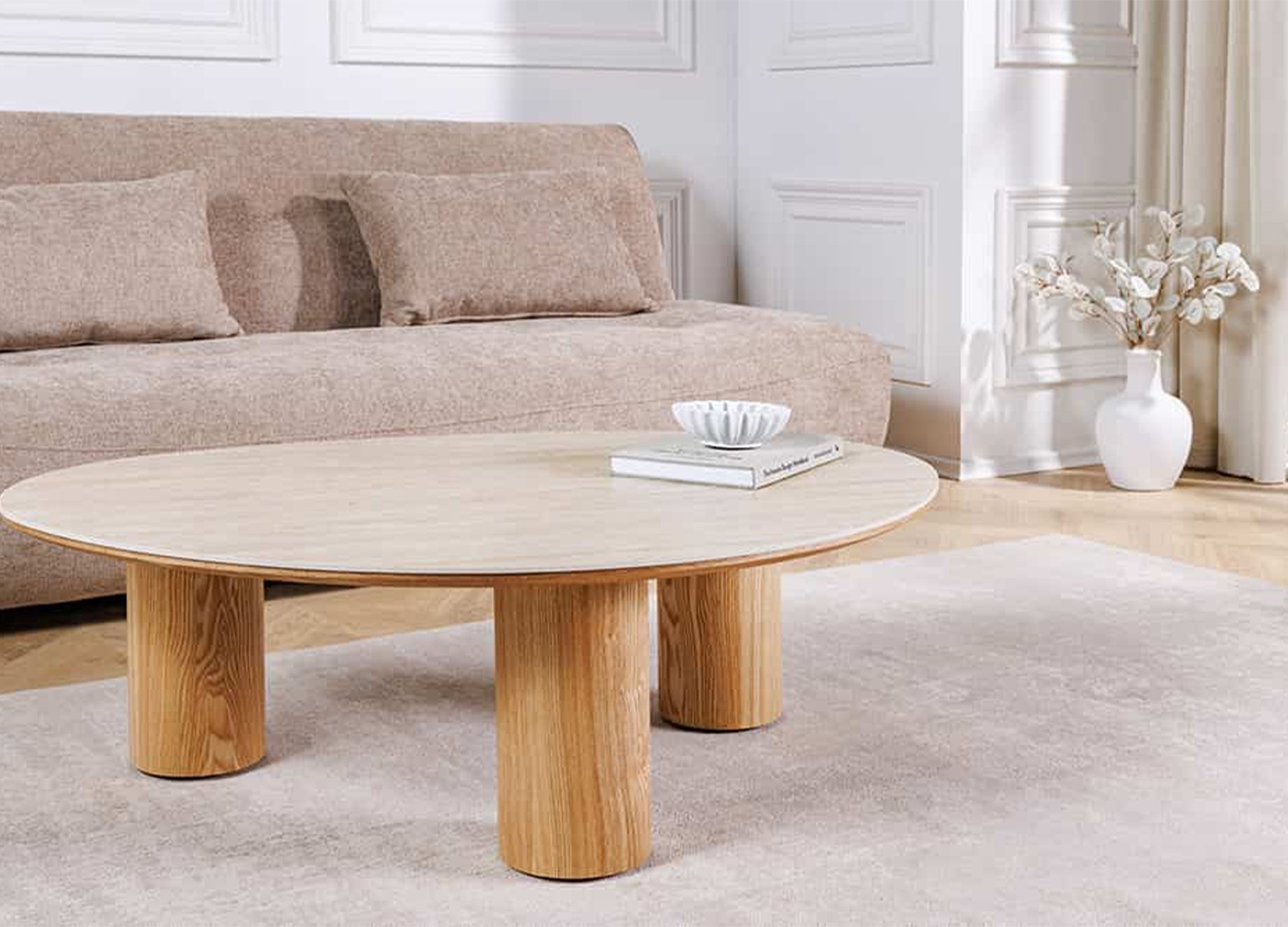 Table basse organique NÉRAYA en céramique travertin et piètement aspect chêne dans un salon lumineux