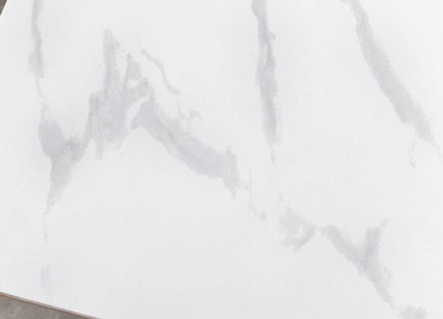 Zoom sur le veinage effet marbre du plateau en céramique blanche de la table KAVEN 120 cm