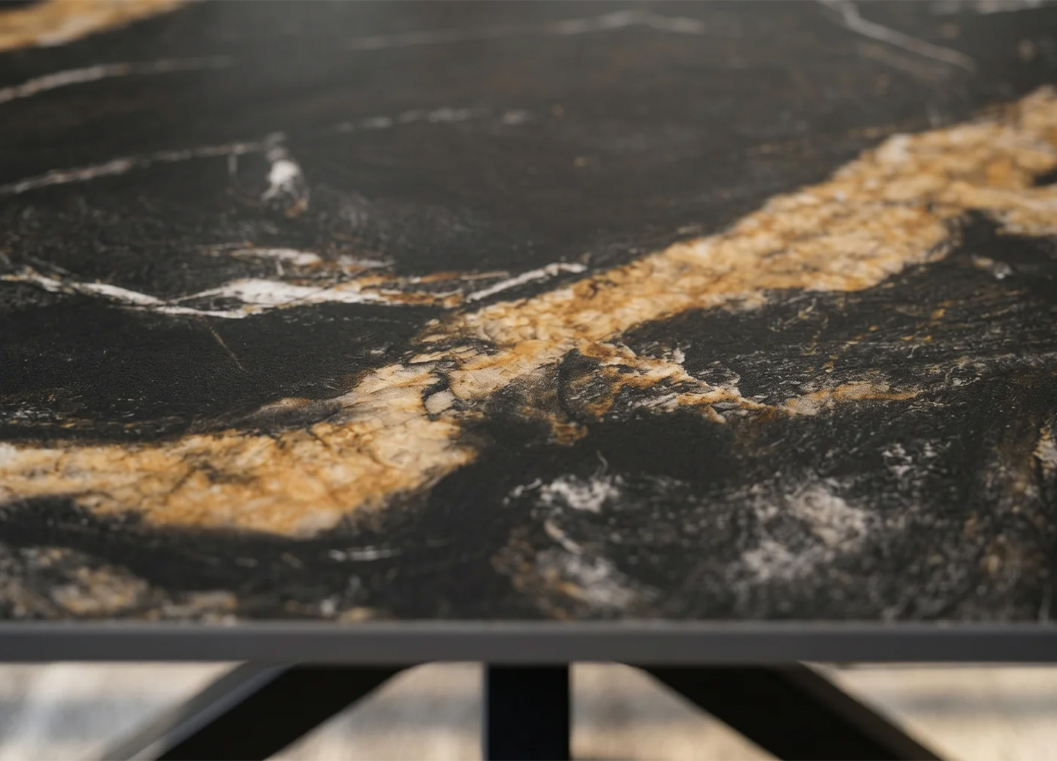 Gros plan sur le plateau céramique noir et or de la table KAVEN 180 cm