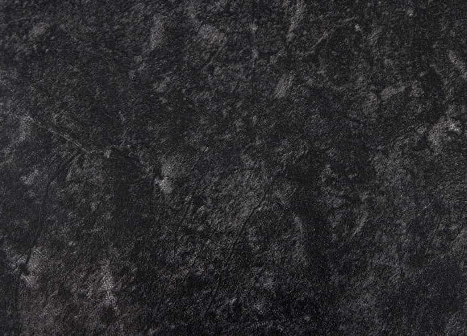 Gros plan sur la texture effet pierre du plateau en céramique anthracite de la table KAVEN