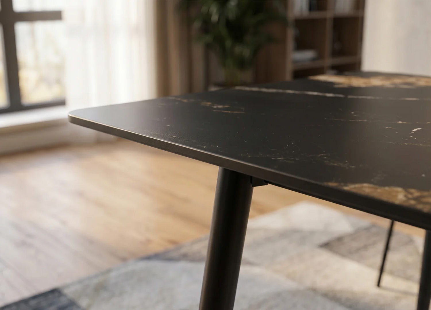 Zoom sur les coins arrondis du plateau en céramique noir et or de la table KAVEN