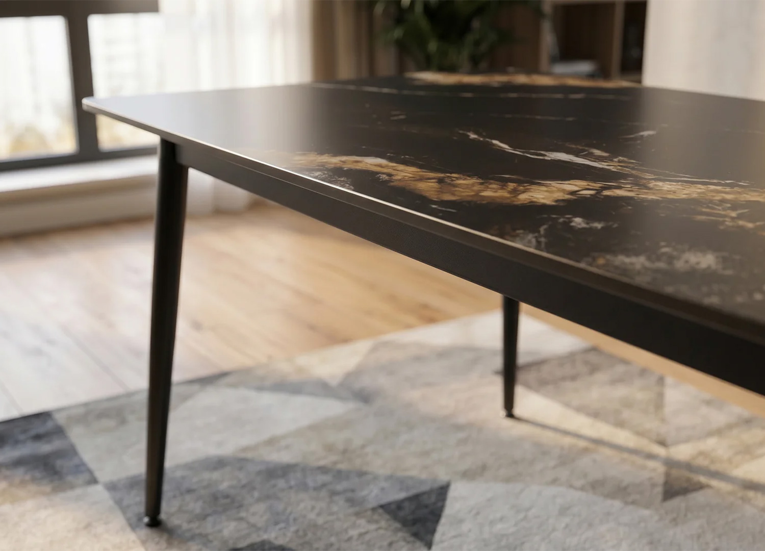 Gros plan sur la texture du plateau céramique noir avec reflets dorés de la table KAVEN