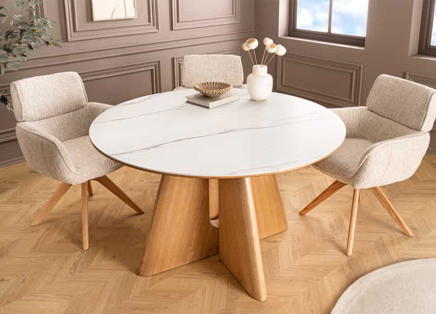 Table à manger ronde ÉLIORA effet marbre blanc dans une salle à manger moderne avec chaises beiges