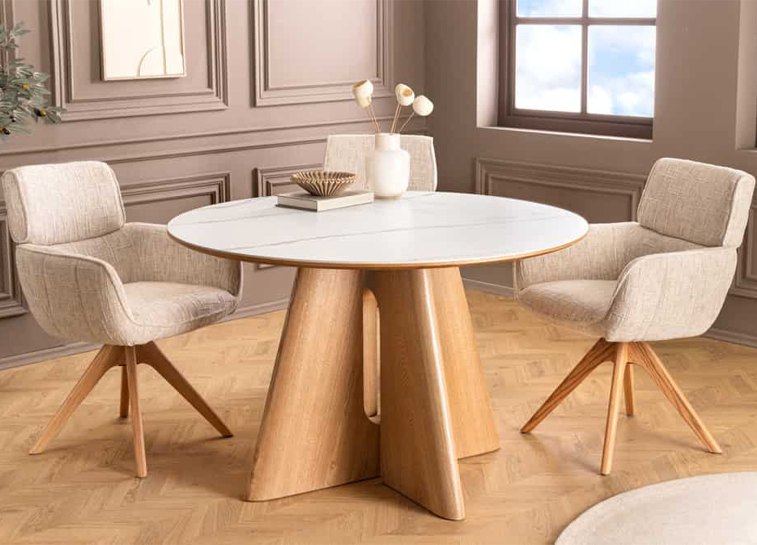 Vue de face de la table ronde ÉLIORA avec plateau effet marbre blanc et chaises en tissu beige