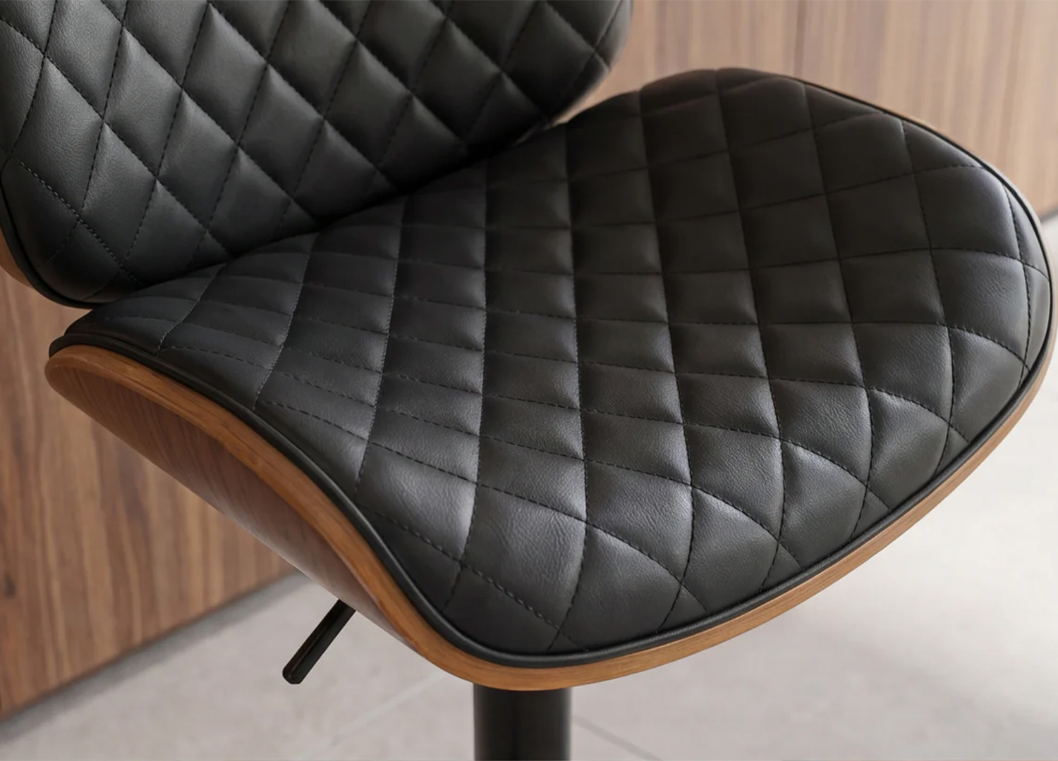 Gros plan sur les coutures et finitions du dossier matelassé noir du tabouret ARMAN