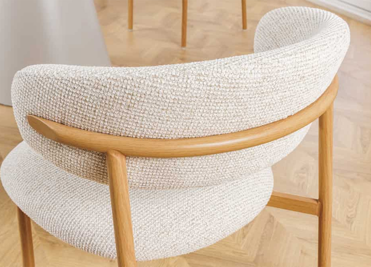 Zoom sur le tissu beige texturé et le pied effet chêne clair de la chaise ALBANE