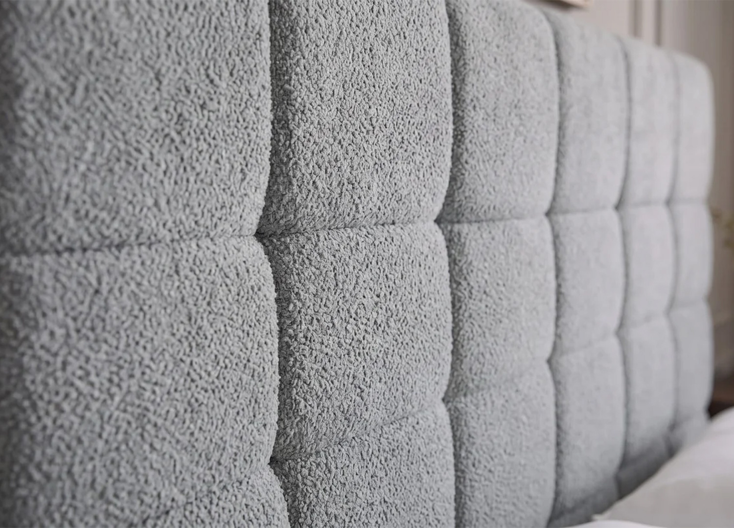 Détail de la tête de lit capitonnée du lit MÉRÉA en tissu bouclé gris